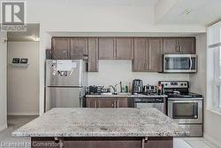 Kitchen with stainless steel appliances, a center island, and dark brown cabinetry - 