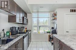 Kitchen featuring visible vents, light stone counters, stainless steel appliances, dark brown cabinets, and a sink - 