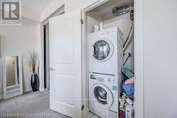 Laundry area featuring laundry area, light colored carpet, and stacked washer and clothes dryer - 