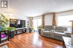 Living room with a textured ceiling, wood finished floors, and visible vents - 