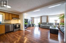 Kitchen featuring appliances with stainless steel finishes, open floor plan, brown cabinets, and under cabinet range hood - 