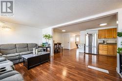 Living area featuring baseboards, a textured ceiling, visible vents, and dark wood-style flooring - 