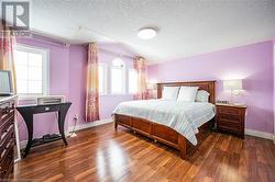 Bedroom with vaulted ceiling, dark wood-type flooring, a textured ceiling, and baseboards - 