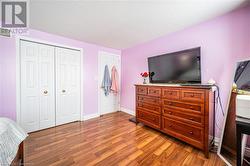 Bedroom with a closet, a textured ceiling, visible vents, and wood finished floors - 