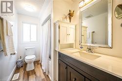 Bathroom with a textured ceiling, visible vents, wood finished floors, and vanity - 