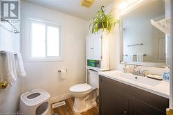 Half bathroom featuring toilet, wood finished floors, visible vents, vanity, and baseboards - 