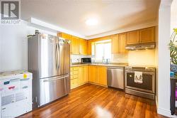 Kitchen featuring extractor fan, dark wood finished floors, stainless steel appliances, and light countertops - 