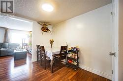 Dining area featuring a textured ceiling, dark wood-style flooring, and baseboards - 