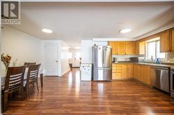 Kitchen featuring a sink, backsplash, stainless steel appliances, and dark wood-style flooring - 