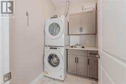 Clothes washing area with stacked washer / drying machine, cabinet space, and a sink - 