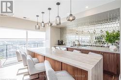 Kitchen featuring visible vents, brown cabinets, decorative light fixtures, light countertops, and a sink - 