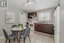 Kitchen featuring dark brown cabinetry, under cabinet range hood, white appliances, a sink, and light countertops - 