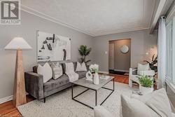 Living room featuring ornamental molding, a textured ceiling, baseboards, and wood finished floors - 