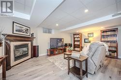 Living room featuring a glass covered fireplace, visible vents, a paneled ceiling, and light wood finished floors - 