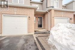 Entrance to property featuring a garage, driveway, and brick siding - 