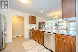 Kitchen featuring light tile patterned flooring, a peninsula, a sink, light countertops, and appliances with stainless steel finishes - 