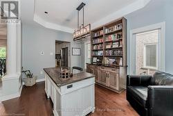 Kitchen featuring freestanding refrigerator, dark wood-style flooring, ornate columns, and open shelves - 