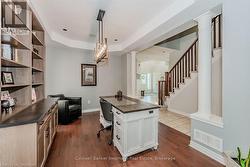 Office space with baseboards, visible vents, dark wood finished floors, a tray ceiling, and ornate columns - 