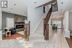 Staircase featuring tile patterned flooring, a fireplace, decorative columns, and baseboards - 