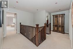 Hallway with light carpet, visible vents, an upstairs landing, and baseboards - 