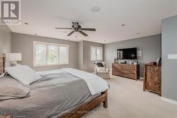 Bedroom featuring baseboards, a ceiling fan, and light colored carpet - 