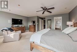 Bedroom featuring light carpet, ensuite bathroom, a ceiling fan, and baseboards - 