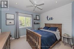 Bedroom featuring baseboards, wooden walls, ceiling fan, and light colored carpet - 