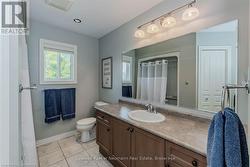 Full bath featuring curtained shower, toilet, vanity, baseboards, and tile patterned floors - 