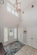 Entryway with light tile patterned floors, a towering ceiling, and an inviting chandelier - 