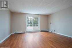 Empty room with a baseboard heating unit, baseboards, and wood finished floors - 