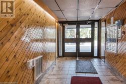 Doorway with a paneled ceiling, wooden walls, mail area, and tile patterned floors - 