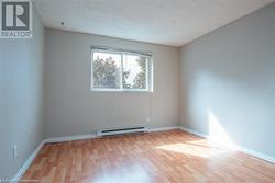 Empty room with baseboard heating, wood finished floors, and baseboards - 