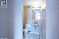 Half bath with a textured ceiling, tile patterned flooring, toilet, a sink, and visible vents - 