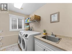 Large practical laundry room with utility sink. Washer/dryer pictured have been replaced with new silver LG machines after this photo was taken. - 