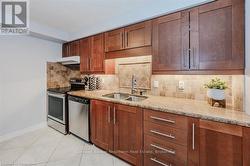 Kitchen featuring stainless steel appliances, backsplash, a sink, light stone countertops, and under cabinet range hood - 