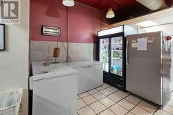 Clothes washing area with laundry area, tile walls, and light tile patterned floors - 