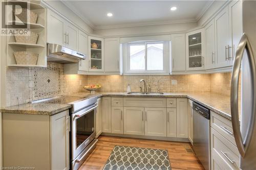 Kitchen featuring under cabinet range hood, stainless steel appliances, a sink, light wood-style floors, and crown molding - 42 Culpepper Drive, Waterloo, ON - Indoor Photo Showing Kitchen With Double Sink With Upgraded Kitchen