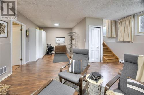 Living area with stairs, a textured ceiling, visible vents, and wood finished floors - 42 Culpepper Drive, Waterloo, ON - Indoor Photo Showing Other Room