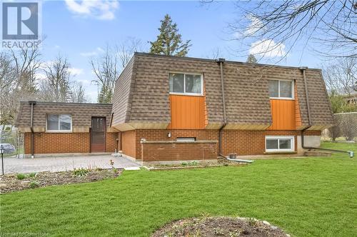 Rear view of house with a shingled roof, a lawn, fence, and mansard roof - 42 Culpepper Drive, Waterloo, ON - Outdoor With Exterior