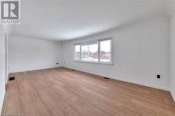 Unfurnished room featuring baseboards, visible vents, and light wood-style floors - 