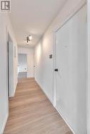 Corridor featuring baseboards and light wood-style floors - 