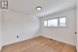 Unfurnished room featuring visible vents, light wood-style flooring, and baseboards - 