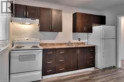 Kitchen with white appliances, a sink, under cabinet range hood, and decorative backsplash - 