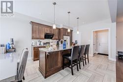 Kitchen with decorative backsplash, appliances with stainless steel finishes, a kitchen breakfast bar, hanging light fixtures, and a kitchen island with sink - 