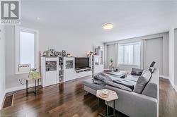 Living room featuring visible vents, baseboards, and wood finished floors - 