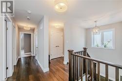 Hall featuring dark wood finished floors, an inviting chandelier, an upstairs landing, and baseboards - 