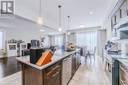 Kitchen featuring pendant lighting, a kitchen island with sink, a sink, light stone counters, and appliances with stainless steel finishes - 