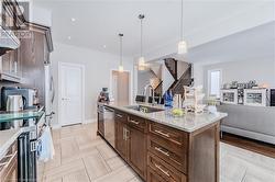 Kitchen featuring stainless steel appliances, a sink, dark brown cabinets, pendant lighting, and open floor plan - 