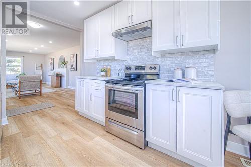 Kitchen featuring decorative backsplash, stainless steel electric range oven, light wood-style floors, and under cabinet range hood - 153 Ballantyne Avenue, Cambridge, ON - Indoor Photo Showing Kitchen