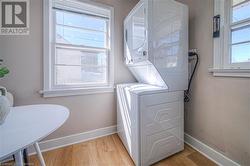 Laundry room featuring stacked washer / drying machine, baseboards, laundry area, and light wood finished floors - 